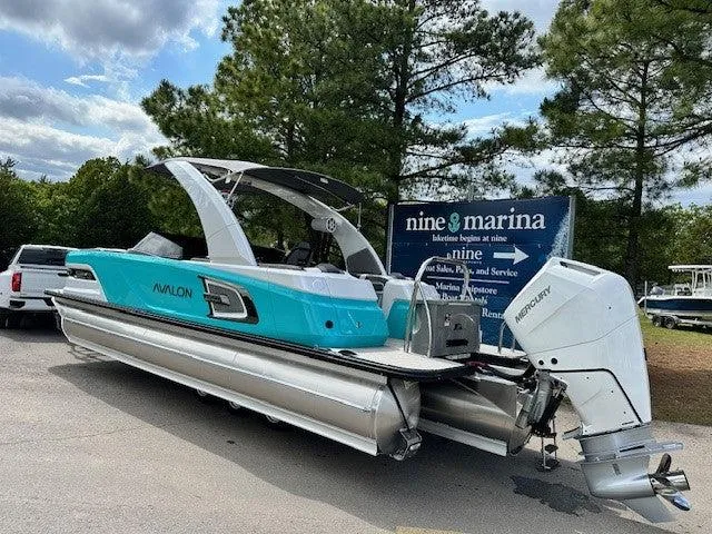 Slide: The Image of 2024 Avalon Quad Lounge Windshield boat at marina, featuring sleek design and powerful Mercury engine. - 12