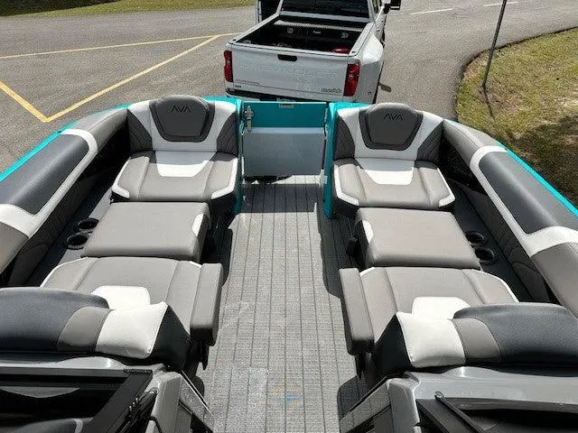 Slide: The Image of 2024 Avalon Quad Lounge Windshield boat interior with luxurious seating, parked near a white truck. - 9