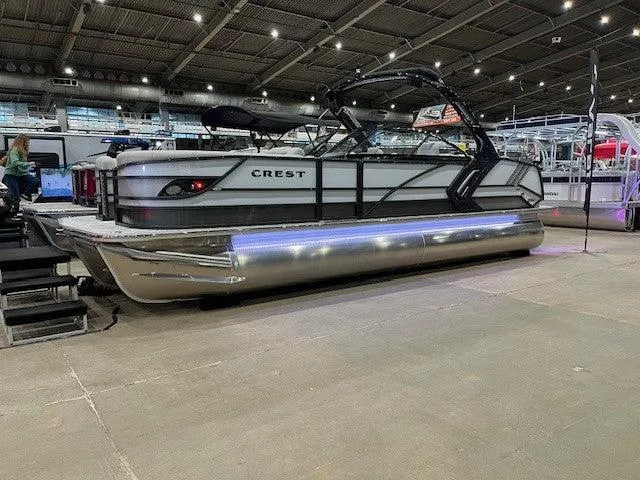 Slide: The Image of 2024 Crest Continental 250 SLRC pontoon boat displayed indoors with LED lighting. - 1