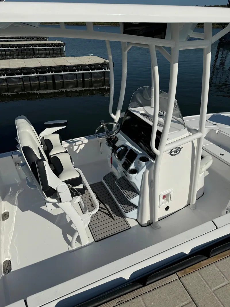Slide: The Image of 2025 Tidewater 2110 Bay Max boat interior with steering console and seating at a dock. - 9