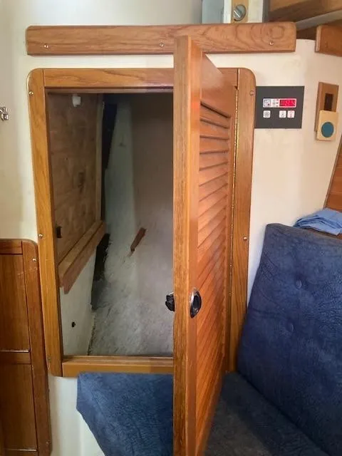 Slide: The Image of Interior of 1998 Catalina 320 sailboat with open wooden cabinet and blue seating. - 27