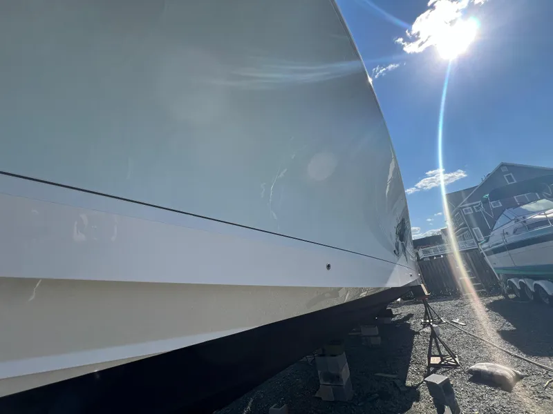 Slide: The Image of 2019 Regulator 41 boat hull under bright sun, docked on gravel. - 16