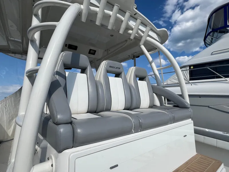 Slide: The Image of 2019 Regulator 41 boat seating with gray and white upholstery under a blue sky. - 47
