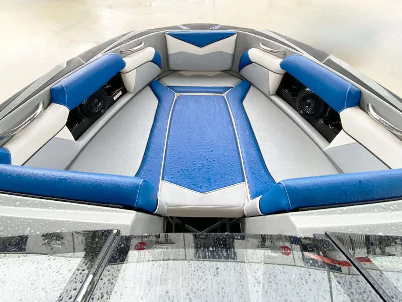 Slide: The Image of 2023 Supreme S240 boat interior with blue and gray seating, wet from rain. - 10