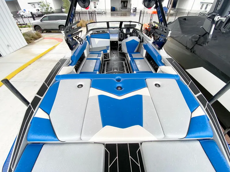 Slide: The Image of 2023 Supreme S240 boat interior with blue and gray seating, docked outdoors. - 6