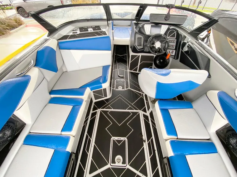 Slide: The Image of 2023 Supreme S240 boat interior with blue and white seating, modern dashboard, and geometric flooring. - 7