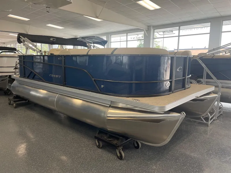 Slide: The Image of 2024 Crest 200L Classic LX pontoon boat in showroom, blue exterior, beige interior. - 0