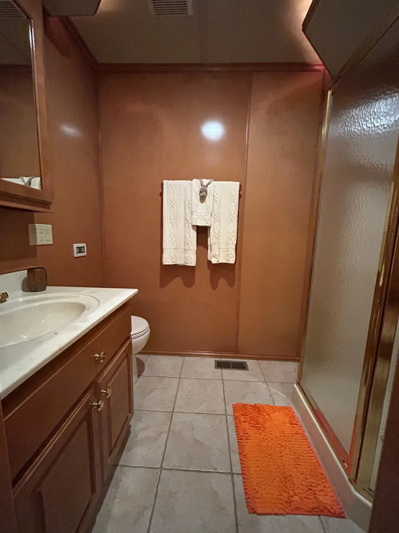 Slide: The Image of Bathroom interior of a 2004 Fantasy Houseboat with wooden cabinetry and orange rug. - 15