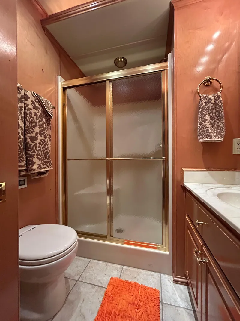 Slide: The Image of Luxurious houseboat bathroom with gold-framed shower, orange accents, and elegant cabinetry. - 16