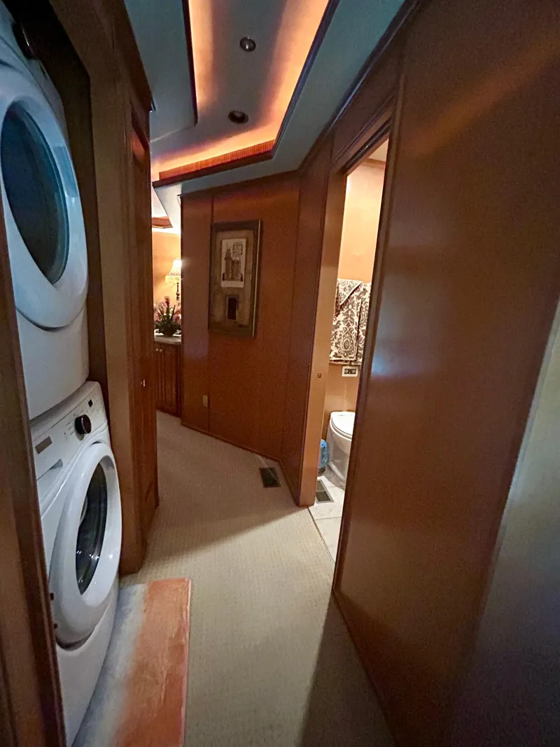 Slide: The Image of Interior of a 2004 Fantasy houseboat featuring a laundry area and hallway with warm lighting. - 18
