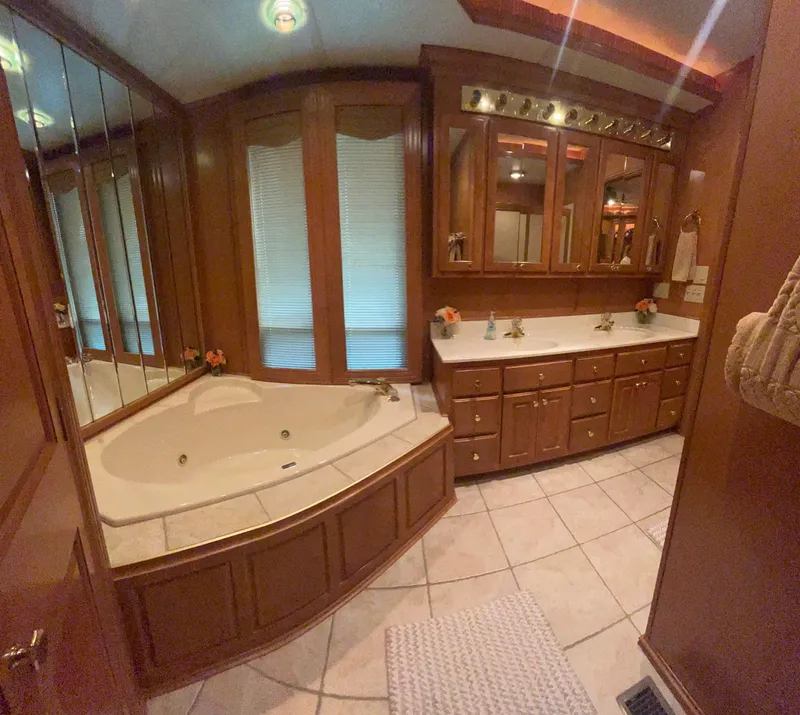 Slide: The Image of Luxurious houseboat bathroom with wooden cabinetry, large mirrors, and a corner bathtub. - 28