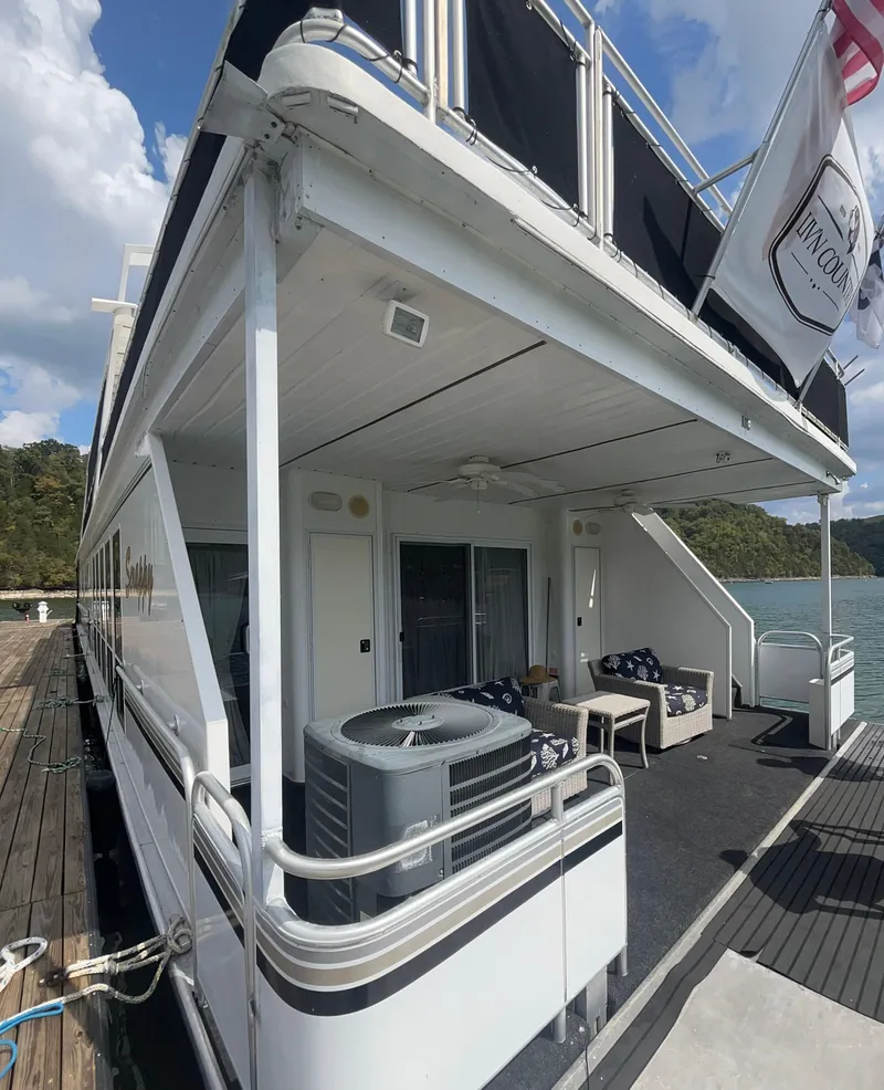 Slide: The Image of Fantasy houseboat docked by a lake, featuring outdoor seating and modern design, 2004 model. - 31