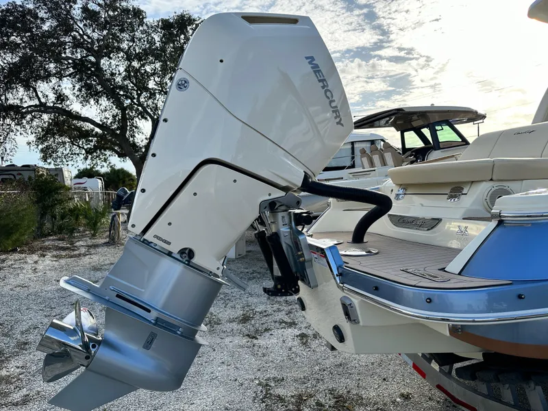 Slide: The Image of 2025 Chris-Craft Launch 28 GT with Mercury outboard engine, docked on gravel, under a cloudy sky. - 3