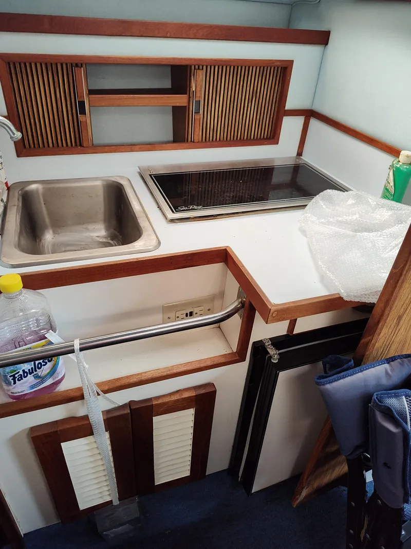 Slide: The Image of 1988 Sea Ray 268 DA boat kitchenette with sink, stove, and storage cabinets. - 11