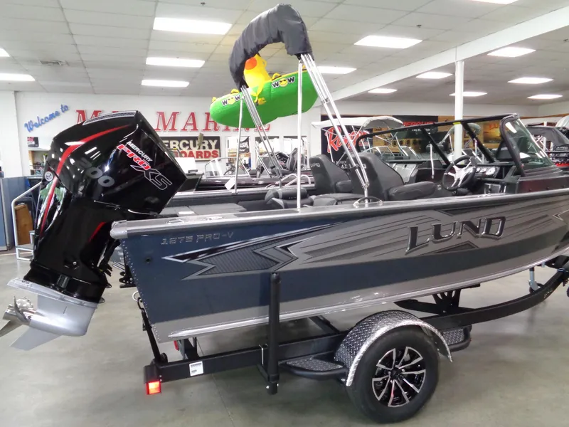 Slide: The Image of 2025 Lund 1875 Pro-V Sport boat displayed indoors with Mercury outboard motor. - 3