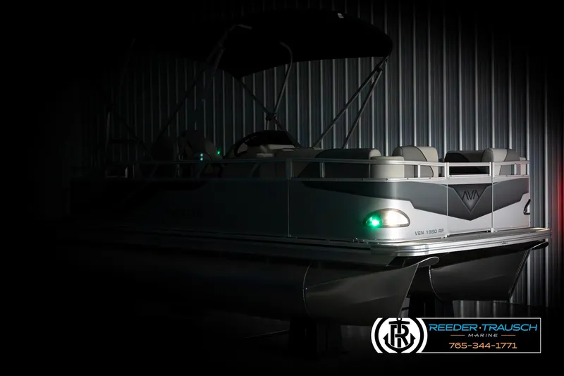 Slide: The Image of 2025 Avalon VEN RF pontoon boat in dimly lit showroom, side view. - 4