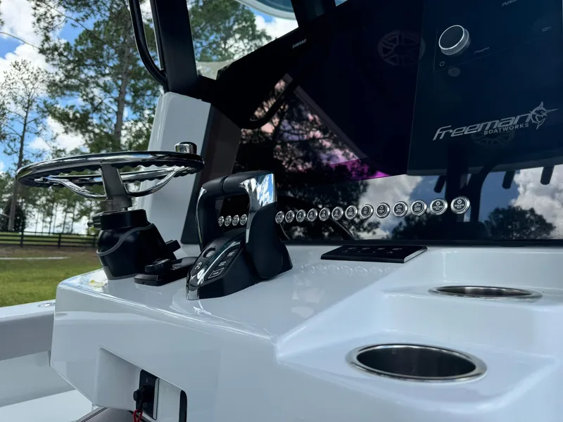 Slide: The Image of 2024 Freeman 28 boat dashboard with steering wheel and controls, set against a scenic background. - 30