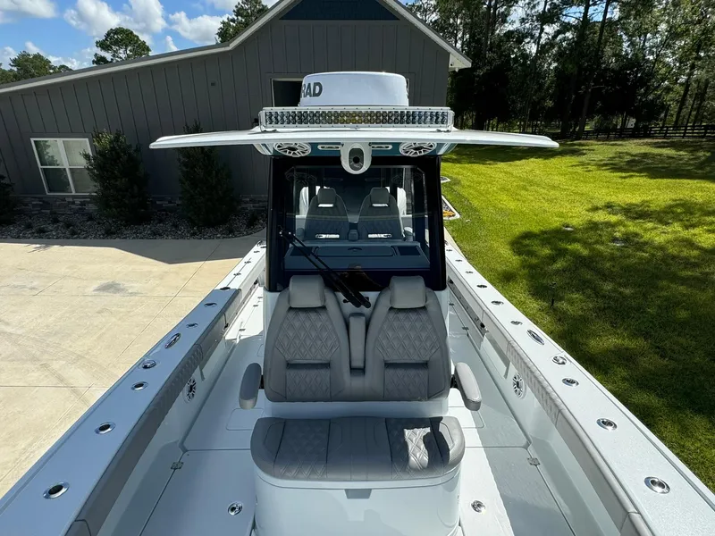 Slide: The Image of 2024 Freeman 28 boat with modern seating and sleek design, parked near a house. - 44