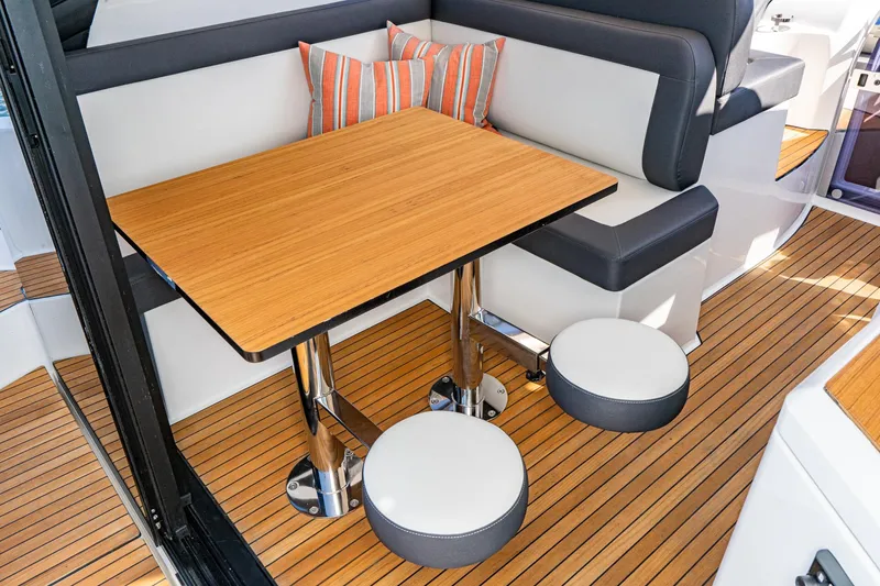 Slide: The Image of 2024 Bavaria SR41 yacht interior with wooden table, cushioned seating, and striped pillows. - 36