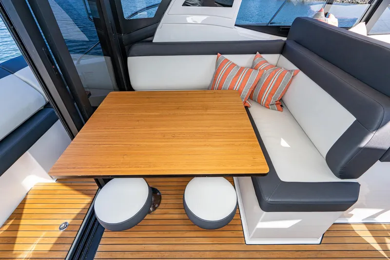 Slide: The Image of 2024 Bavaria SR41 yacht interior with wooden table, cushioned seating, and striped pillows. - 37