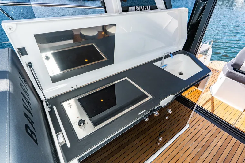 Slide: The Image of 2024 Bavaria SR41 yacht kitchen with stove and sink, featuring sleek design and wooden deck. - 41