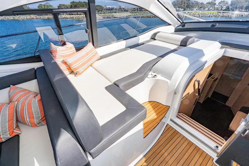 Slide: The Image of 2024 Bavaria SR41 yacht interior with cushioned seating and striped pillows, overlooking serene waters. - 46