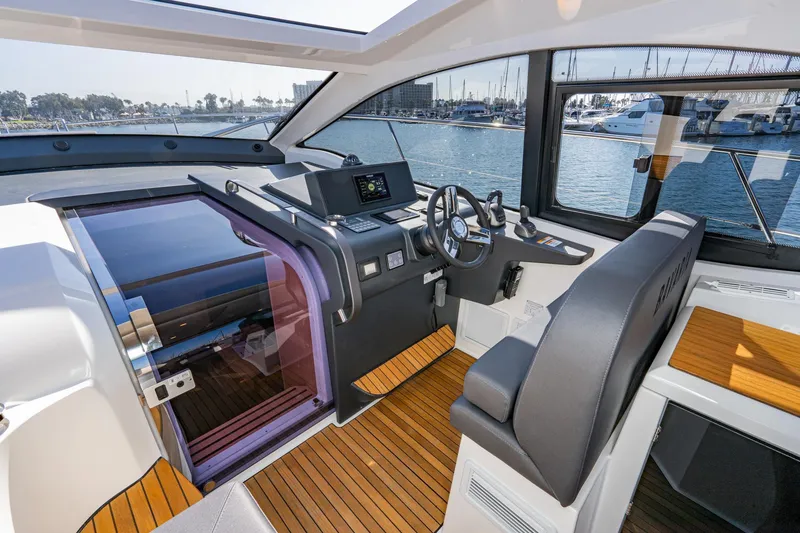 Slide: The Image of 2024 Bavaria SR41 yacht cockpit with modern controls and wooden flooring, docked at marina. - 47