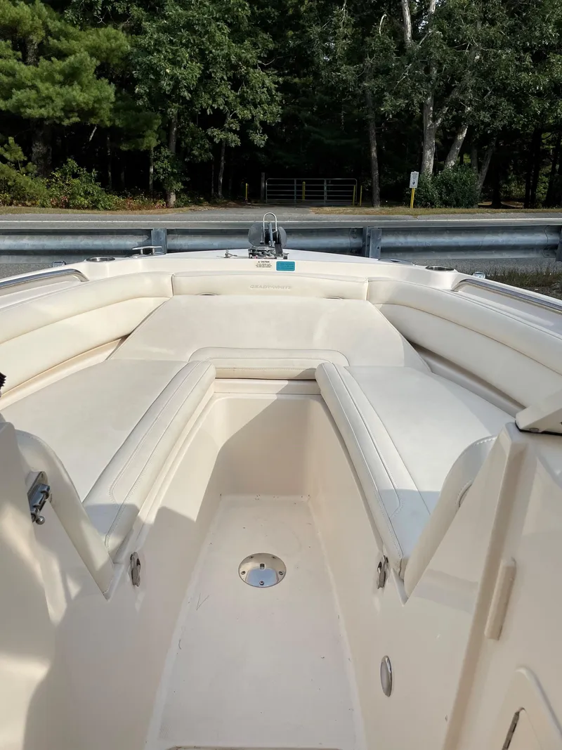 Slide: The Image of 2019 Grady-White 235 Freedom boat interior with cushioned seating, surrounded by lush greenery. - 8