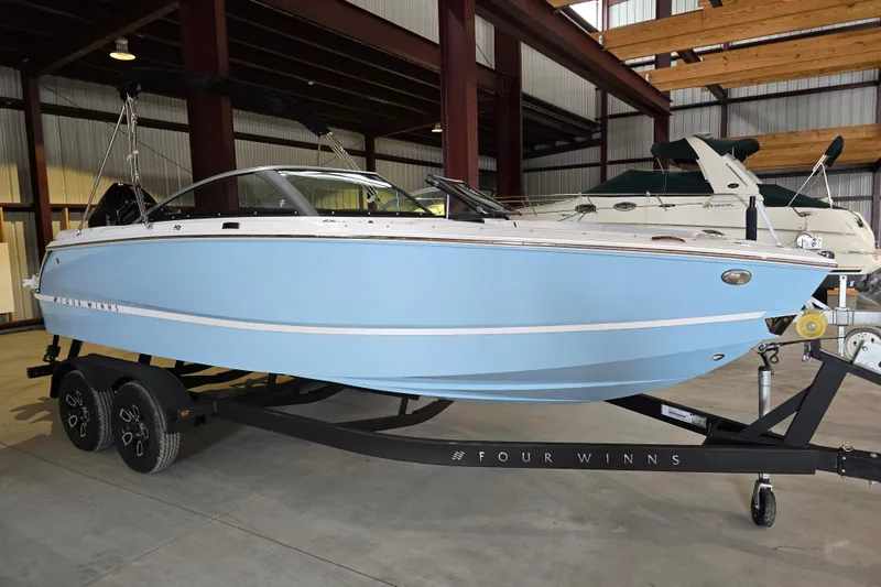 Slide: The Image of 2025 Four Winns H2 OB boat in a showroom, light blue hull on a trailer. - 5