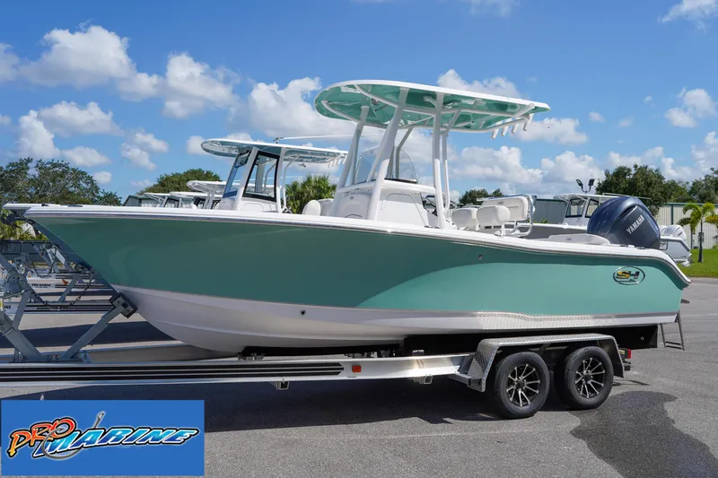 Slide: The Image of 2025 Sea Hunt Ultra 219 boat on trailer, teal hull, clear sky background. - 22