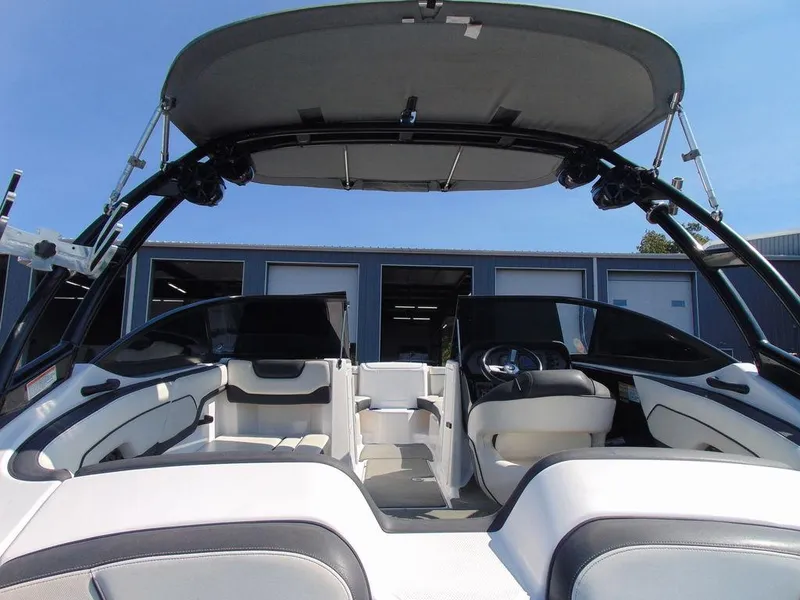 Slide: The Image of 2017 Yamaha Boats AR210 interior with seating and steering, under a canopy, docked outdoors. - 4