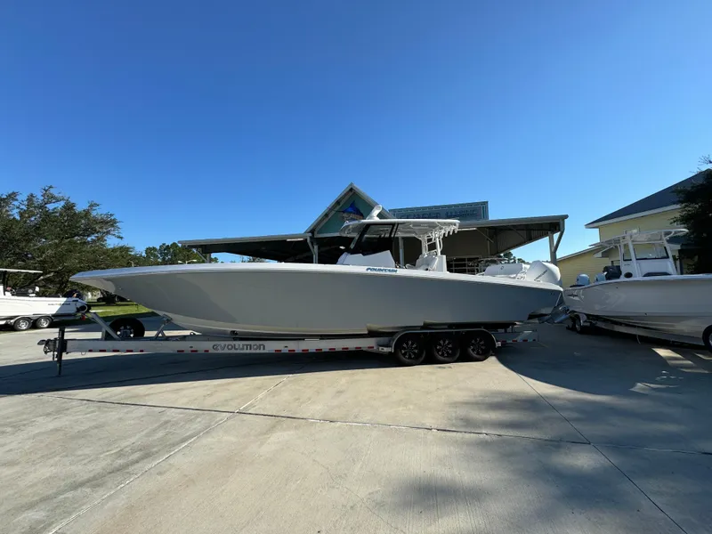 The Image of 2025 Fountain 38TE boat on trailer, parked outdoors under clear blue sky. - 1