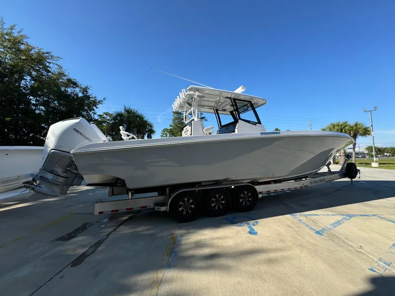 Slide: The Image of 2025 Fountain 38TE boat on trailer, parked outdoors under clear blue sky. - 12