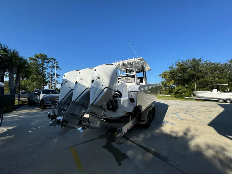 Slide: The Image of 2025 Fountain 38TE boat with triple outboard engines on a trailer in a sunny parking lot. - 14