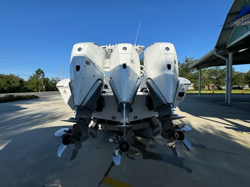 Slide: The Image of 2025 Fountain 38TE boat with triple outboard engines, parked outdoors under clear blue sky. - 16