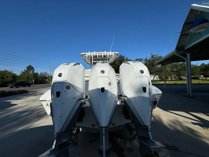 Slide: The Image of 2025 Fountain 38TE boat with triple outboard engines, parked outdoors under clear blue sky. - 17