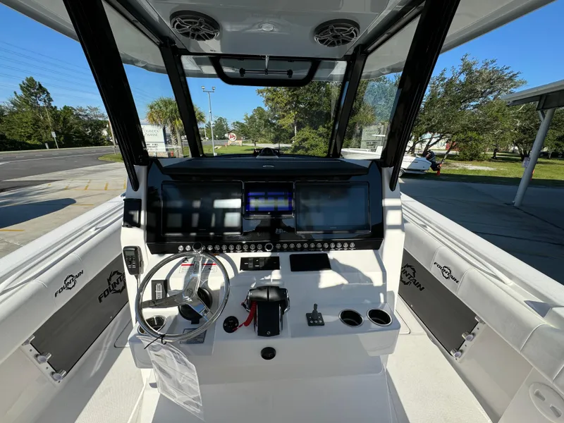 Slide: The Image of 2025 Fountain 38TE boat cockpit with modern controls and steering wheel, parked outdoors. - 29