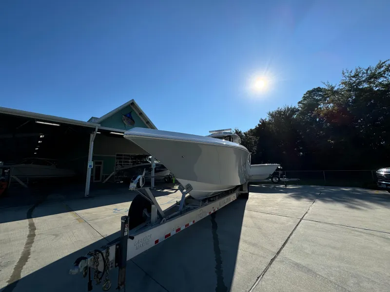 Slide: The Image of 2025 Fountain 38TE boat on trailer under bright sun, parked near a building. - 5