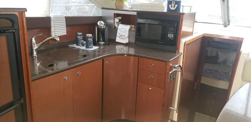 Slide: The Image of 2010 Meridian 441 Sedan yacht kitchen with microwave, sink, and wooden cabinetry. - 15
