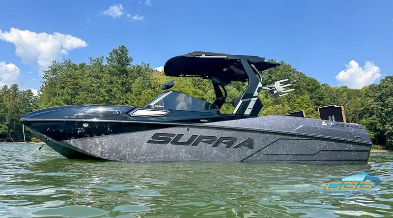 Slide: The Image of 2024 Supra SE boat on a lake, sleek design, black finish, sunny day. - 12