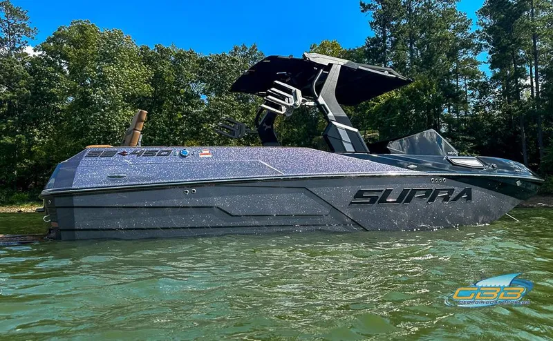 Slide: The Image of 2024 Supra SE boat on water, sleek design, surrounded by trees. - 14