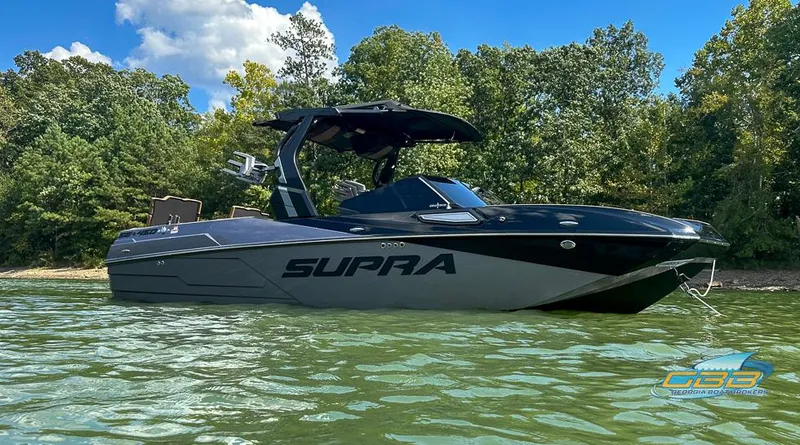 Slide: The Image of 2024 Supra SE boat on a lake, surrounded by trees under a clear blue sky. - 2