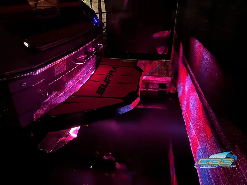 Slide: The Image of 2024 Supra SE boat with vibrant pink underwater lighting at night. - 35