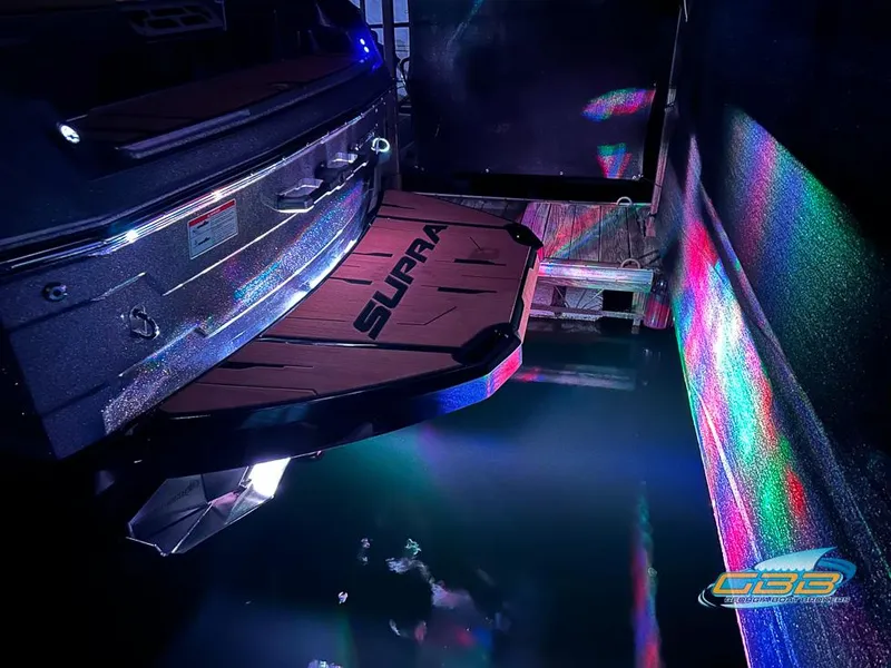 Slide: The Image of 2024 Supra SE boat with illuminated swim platform and colorful reflections on water. - 41