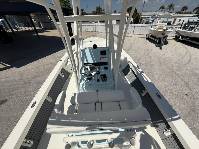 Slide: The Image of 2025 Pathfinder 2600 HPS boat interior with steering console and seating, parked outdoors. - 11