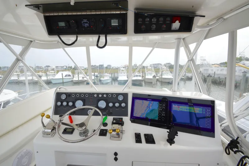 Slide: The Image of 1998 Post 42 Convertible yacht helm with navigation screens and controls in marina setting. - 26