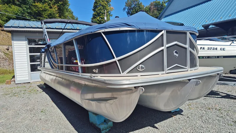 Slide: The Image of 2023 South Bay 523E 2.75 pontoon boat with blue cover, parked outdoors. - 3