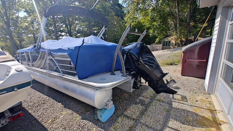 Slide: The Image of 2023 South Bay 523E 2.75 pontoon boat with blue cover and outboard motor. - 5