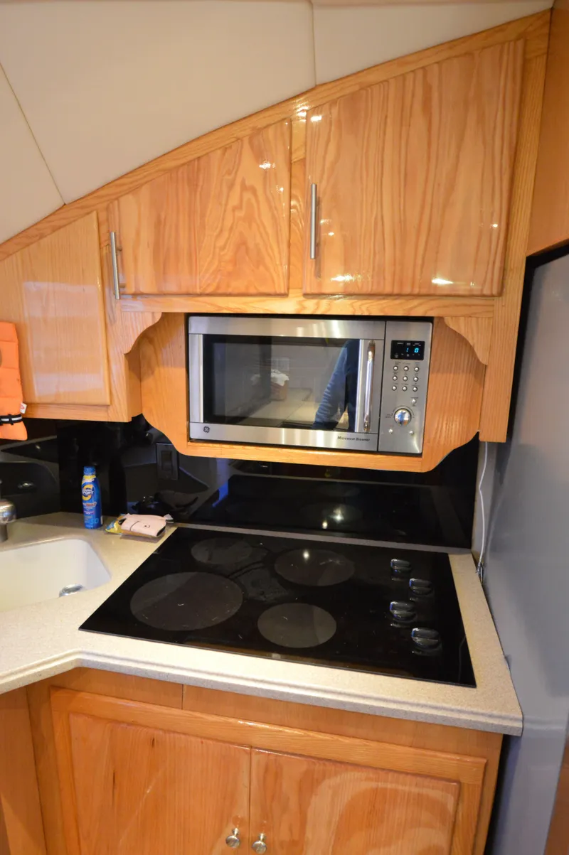 Slide: The Image of 2004 Chesapeake 58 boat kitchen with microwave, stovetop, and wooden cabinetry. - 13