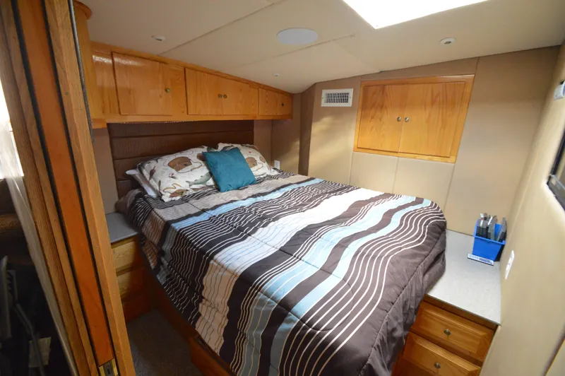 Slide: The Image of Cozy bedroom in 2004 Chesapeake 58 boat with wood cabinets and striped bedding. - 18